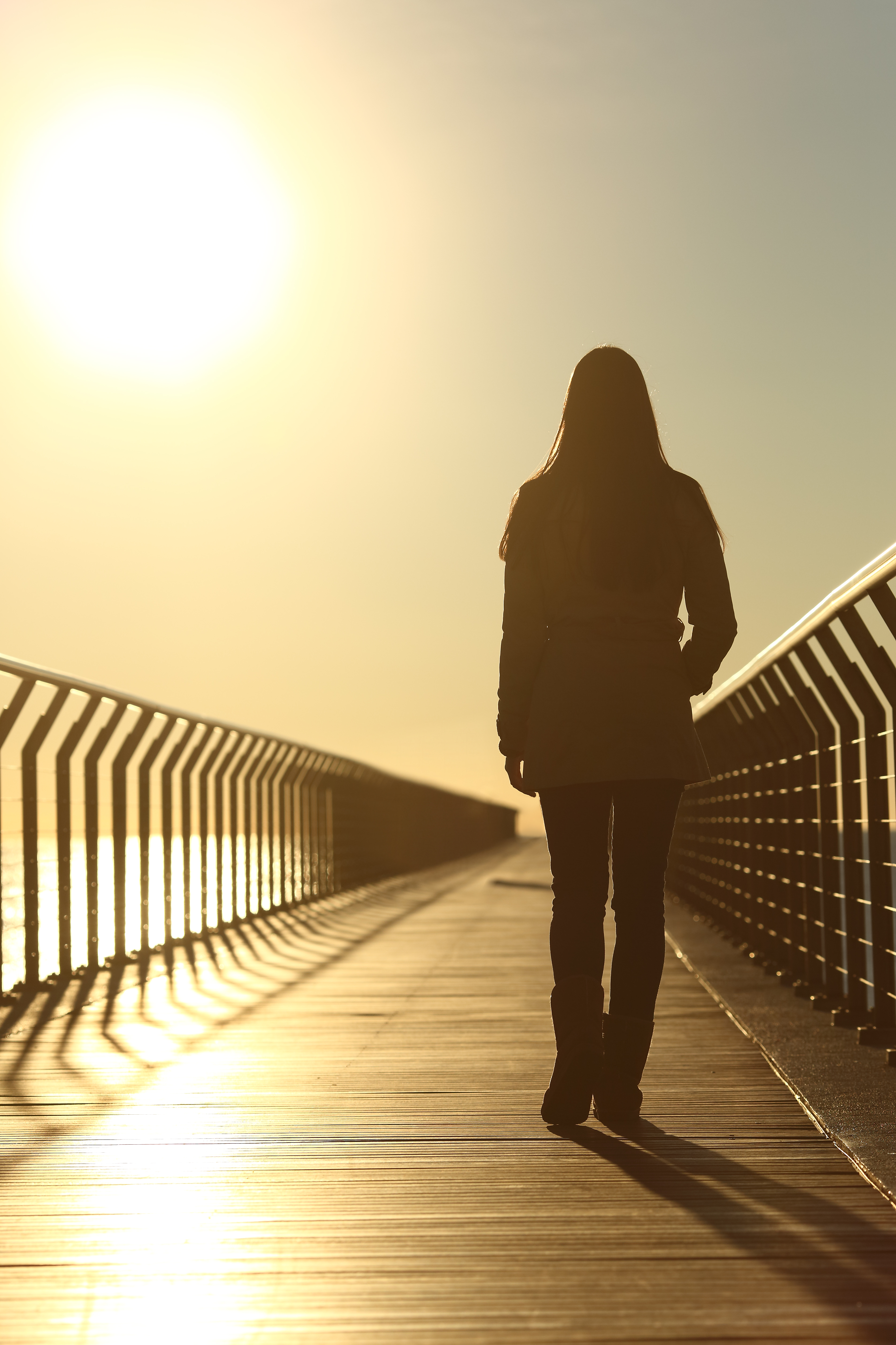 Sad woman silhouette walking alone at sunset